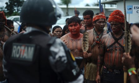 Indians from the Munduruku, Juruna, Kayapo, Xipaya, Kuruaya, Asurini, Parakana, and Arara tribes in Tapajos and Teles Pires river basins face a riot police officer as they invade the main construction site of the Belo Monte hydroelectric dam site in protest against the dam's construction, in Vitoria do Xingu, near Altamira in Para State, May 2, 2013.