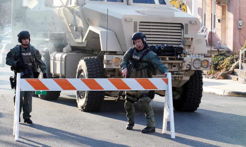 Police stand near an armored vehicle parked on the street in front of a property being searched in Pennsburg, Pennsylvania.