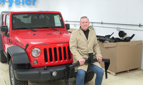 Wes Lutz, owner of a dealership in Jackson, Michigan, sits with a trailer hitch that is to be installed on certain Jeep Grand Cherokees and Libertys that have been recalled to add protection to their gas tanks in rear collisions.