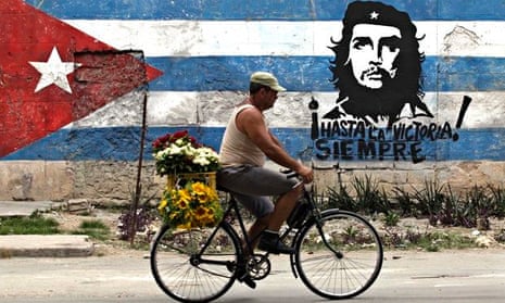 A man rides his bicycle past a mural of rebel hero Ernesto 'Che' Guevara and a Cuban flag in Havana