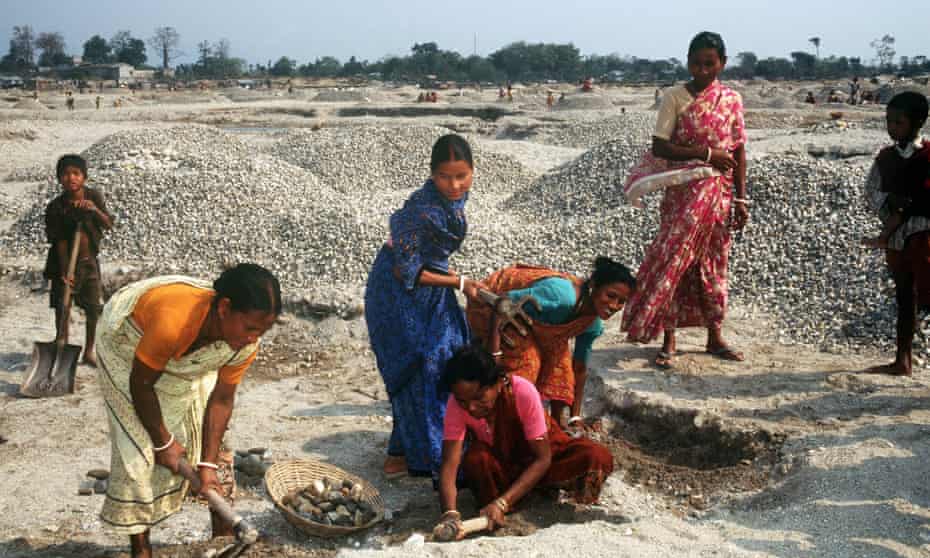 Indian women and children work as stone crushers.