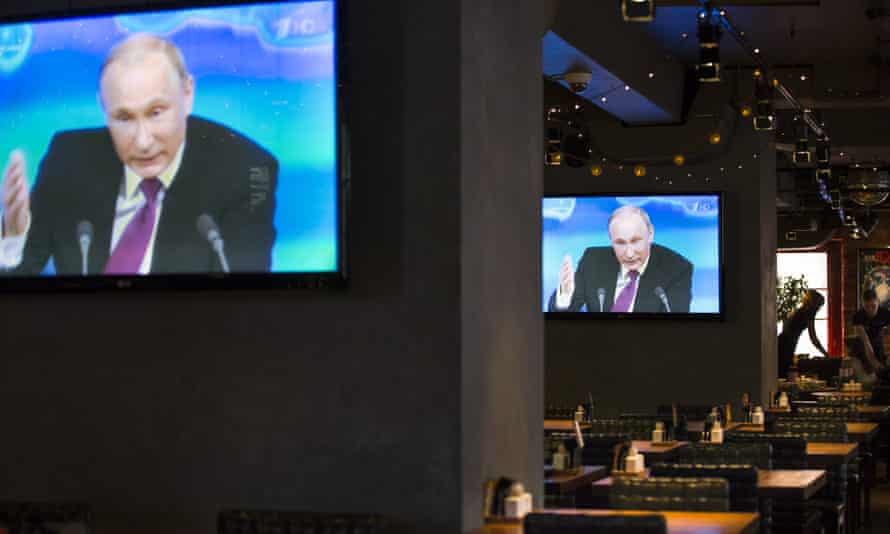 Russian president Vladimir Putin on TV screens in Moscow during a three-hour press conference.