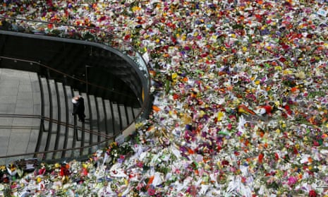A man arrives with a bunch of flowers in Martin Place in Sydney on Thursday. Tens of thousands of people have laid floral tributes to the two victims.