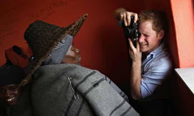 Prince Harry takes a photograph during a visit to a herd boy night school