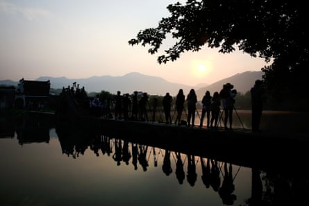 HUANGSHAN, CHINA - JUNE 12: Photographers take photos of sunrise on June 12, 2014 in the ancient Hongcun Village, China.