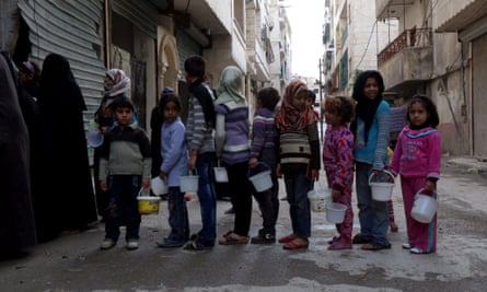 Syrian children queue for food aid from a community kitchen in the Myassar district of Aleppo.