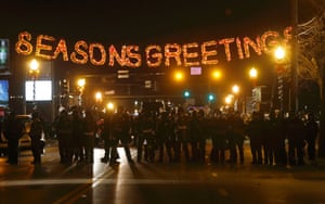 Threatening police gathered under Seasons Greetings sign at ferguson
