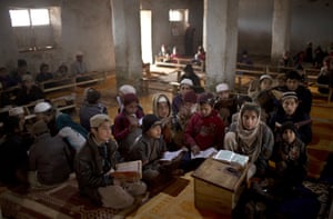 Islamabad, Pakistan Afghan refugee children listen to a boy reading verses of the Qur'an, during a daily class on how to read the alphabet and verses of the holy scripture