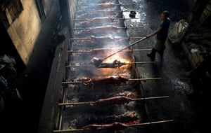 Manila A worker applies oil to pigs on a barbecue for the busy holiday season. Lechon, or roasted pig, has always been a regular fare at Philippine festivities, especially during Christmas and New Year celebrations