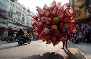 Hanoi, Vietnam A man sells Santa Claus shaped balloons on the street in the morning sun