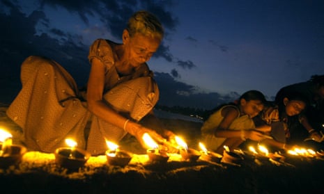 A Sri Lankan woman lights an earthenware lamp as she sits with others at Unawatuna Beach in Galle, some 123 km south of Colombo, 26 January 2005.  Sri Lankans lit some 40,000 lamps in memories of those killed by tsunami waves which struck 26 December 2004