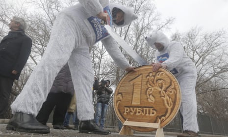 Communist party activists saw through a replica of the Russian rouble at an anti-government protest in Moscow on Monday.  EPA/MAXIM SHIPENKOV