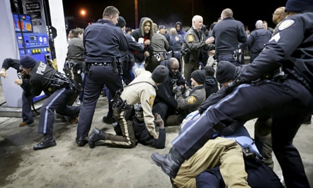 Police try to control a crowd, on the lot of a gas station following a shooting in Berkeley, Missouri.