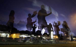 Protesters march as lightning flashes in the distance in Ferguson, Missouri on 20 August 2014 after a police officer shot unarmed Michael Brown.