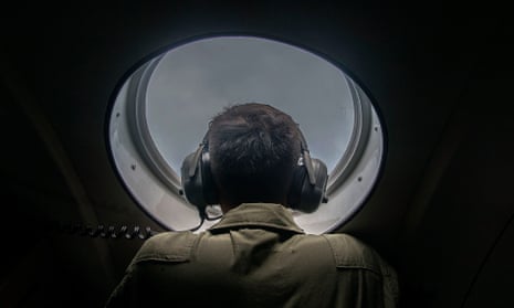 A member of the Indonesian military looks out of the window during a search and rescue (SAR) operation for missing Malaysian air carrier AirAsia flight QZ8501, over the waters of the Java Sea on December 29, 2014.