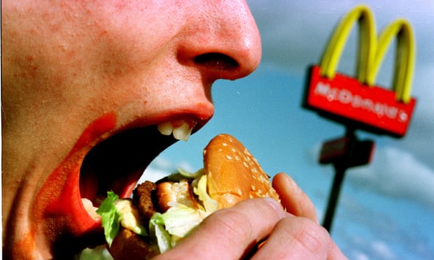 person eating burger in front of mcdonalds sign