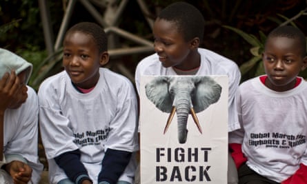 Young demonstrators sit with a placard as they prepare to take part in the "Global March for Elephants and Rhinos" to raise awareness Nairobi, Kenya Saturday, Oct. 4, 2014.