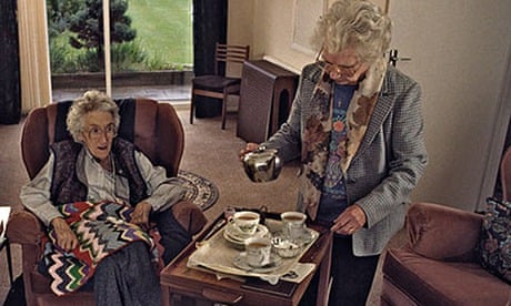 Home help serving up tea and cakes to elderly woman