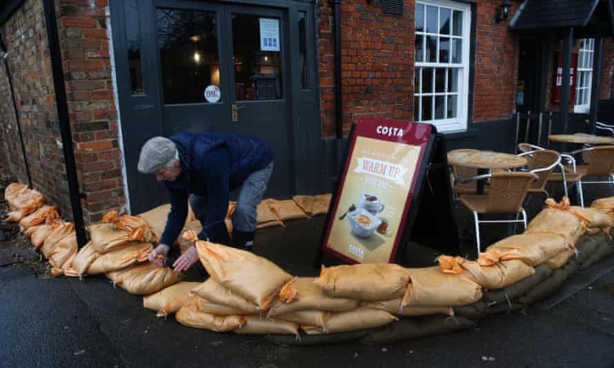 A resident moves sandbags to surround a property from the floods, in the centre of the village of Datchet, England