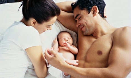 Couple lying in bed with newborn baby