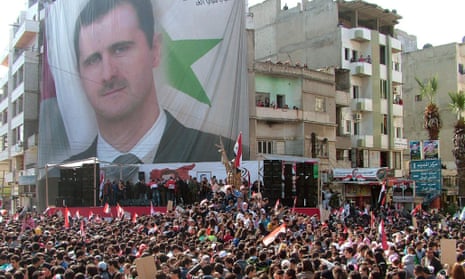 A handout picture made available by the official Syrian Arab News Agency shows Syrian citizens carrying pictures of President Bashar Assad.