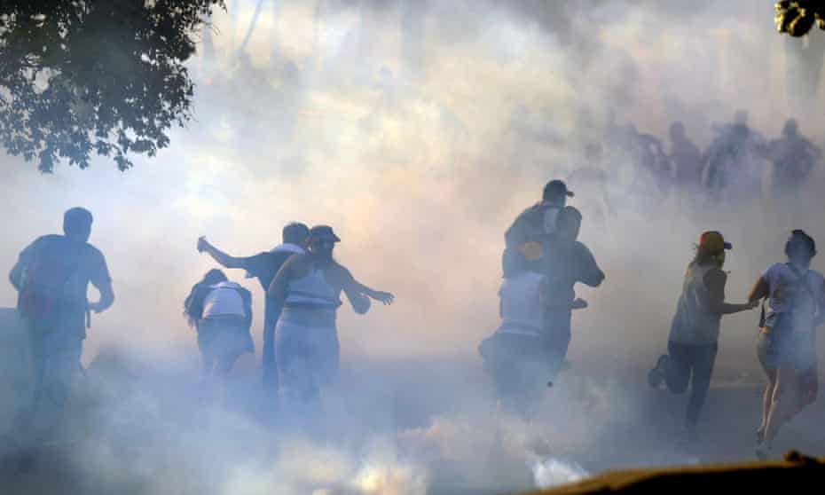 Students flee after the National Guard fires tear gas  in Caracas on Sunday.