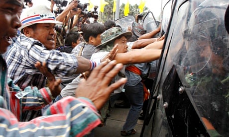 Farmers push against riot police during a protest in Bangkok