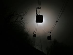 Gondolas are shrouded in fog as they travel between the biathlon and cross country skiing venues .