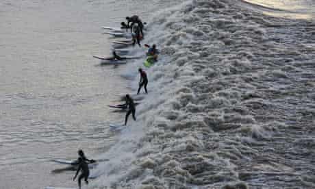 Surfers attempt to ride waves caused by floodwaters at the river Severn Bore in Newnham