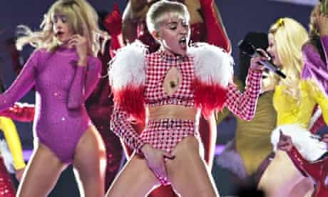 A scantily clad Miley Cyrus on stage in LA, hand on crotch