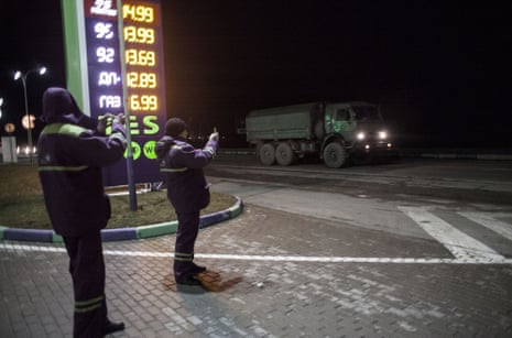 Gas station employees take pictures of a convoy of 20 Russian armoured personnel carriers and trucks full of troops pictured in the evening 3km from Simferopol of Crimea where they are reportedly heading on February 28, 2014 near Simferopol, Crimea, Ukraine.