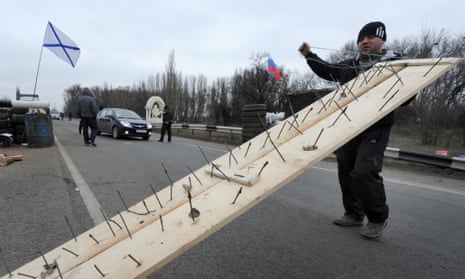 One of the  men who called themselves members of local militia carries a makeshift road spike barrier to block a highway that connect Black Sea Crimea peninsula to mainland Ukraine at their checkpoint near the city of Armyansk, on February 28, 2014.