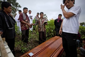Relatives pray during the burial of a victim who was killed after being hit by pyroclastic smoke from the eruption of Mount Sinabung.