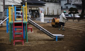 A man uses a roller near a Geiger counter, measuring a radiation level of 0.207 microsievert per hour, during nuclear radiation decontamination work at a park in Koriyama/
