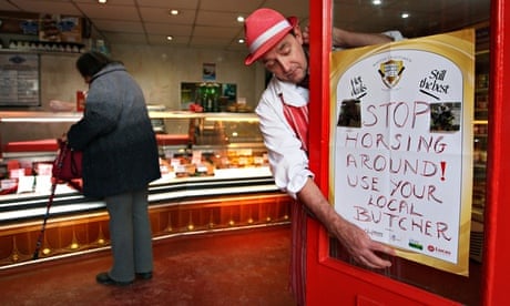 Butcher in red hat and apron puts sign on his door: Stop horsing around, use your local butcher!