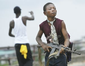 A child Liberian militia soldier loyal to the government walks away from firing while another taunts enemies on July 30, 2003 in Monrovia, Liberia.  Sporadic clashes continued between government forces and rebel fighters in the fight for control of Monrovia.
