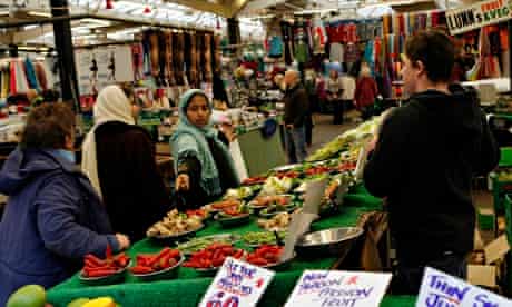 A fruit stall in Leicester Market with various ethnic groups
