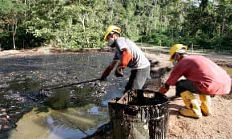Oil workers clean up a contaminated pool in Taracoa