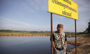 A man stands in front of a reservoir where the Mae Moh power plant had released large quantities of waste water continuously. 