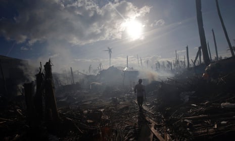 A man walking through smoke from fires in a part of Tolosa devastated by Typhoon Haiyan