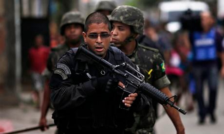 Policeman escorts Brazilian Army in Mare slums complex in Rio de Janeiro
