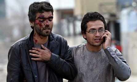 An Afghan man who was injured in the Taliban attack is helped from the scene