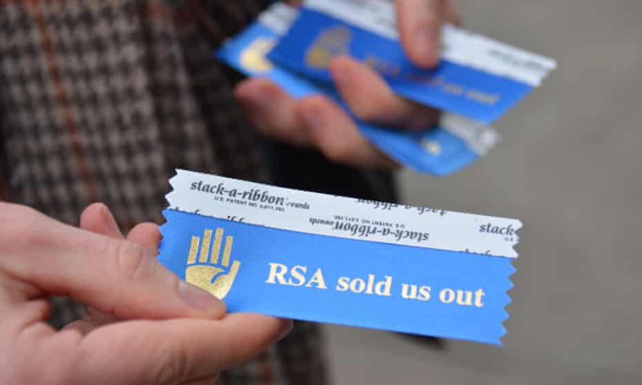 A man hands out 'RSA sold us out' ribbons near Moscone West for the badges of people attending the RSA conference.
