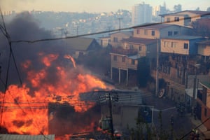 Firefighters try to put out a fire in the area where a forest fire burned several neighbourhoods in the hills on the edge of the city. At least 11 people were killed and 500 houses destroyed over the weekend by the fire.