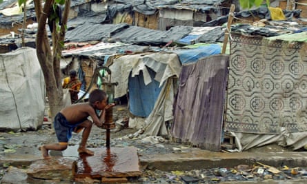 A boy drinks water from a pump near a slum on the banks of the Yamuna river in Delhi.