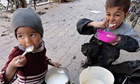 Two children eat food distributed to them in the besieged Yarmouk refugee camp.