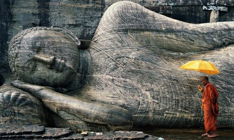 A monk by a Buddha statue in Gal Vihara, Sri Lanka