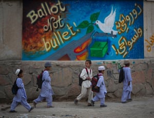 Schoolchildren walk past election graffiti on their way home on the outskirts of Kandahar