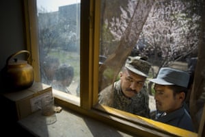 An Afghan soldier and a police officer peek through a window as they queue outside a school in Kabul on the last day of voter registration for the elections