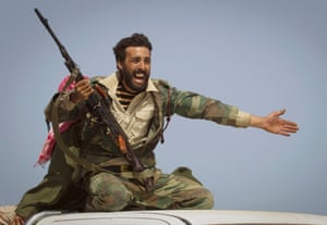 A Libyan rebel urges people to flee as Gaddafi's forces start shelling the frontline outside Bin Jawaad